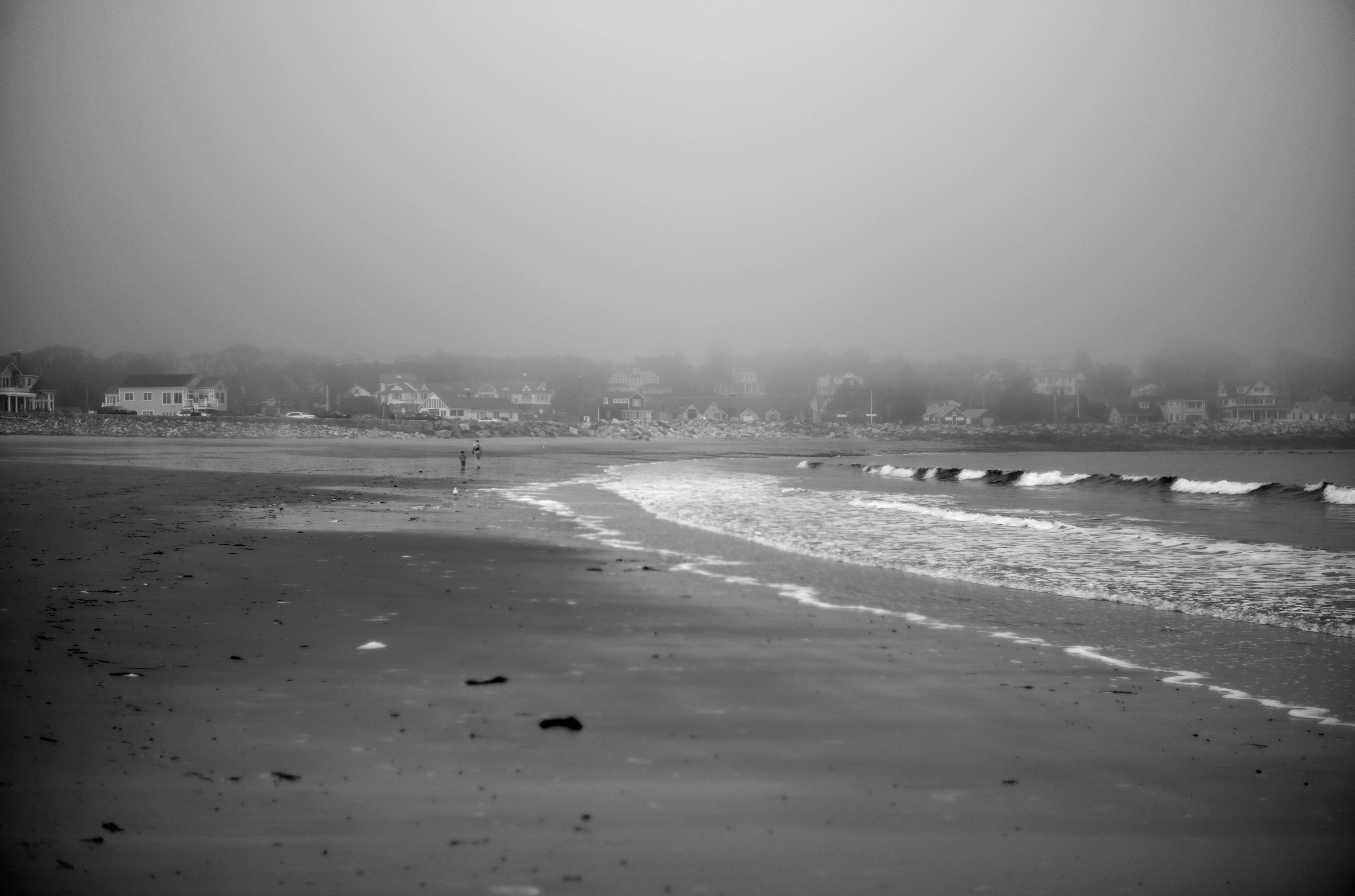 Two figures at the surf line, wave foam curving across the frame