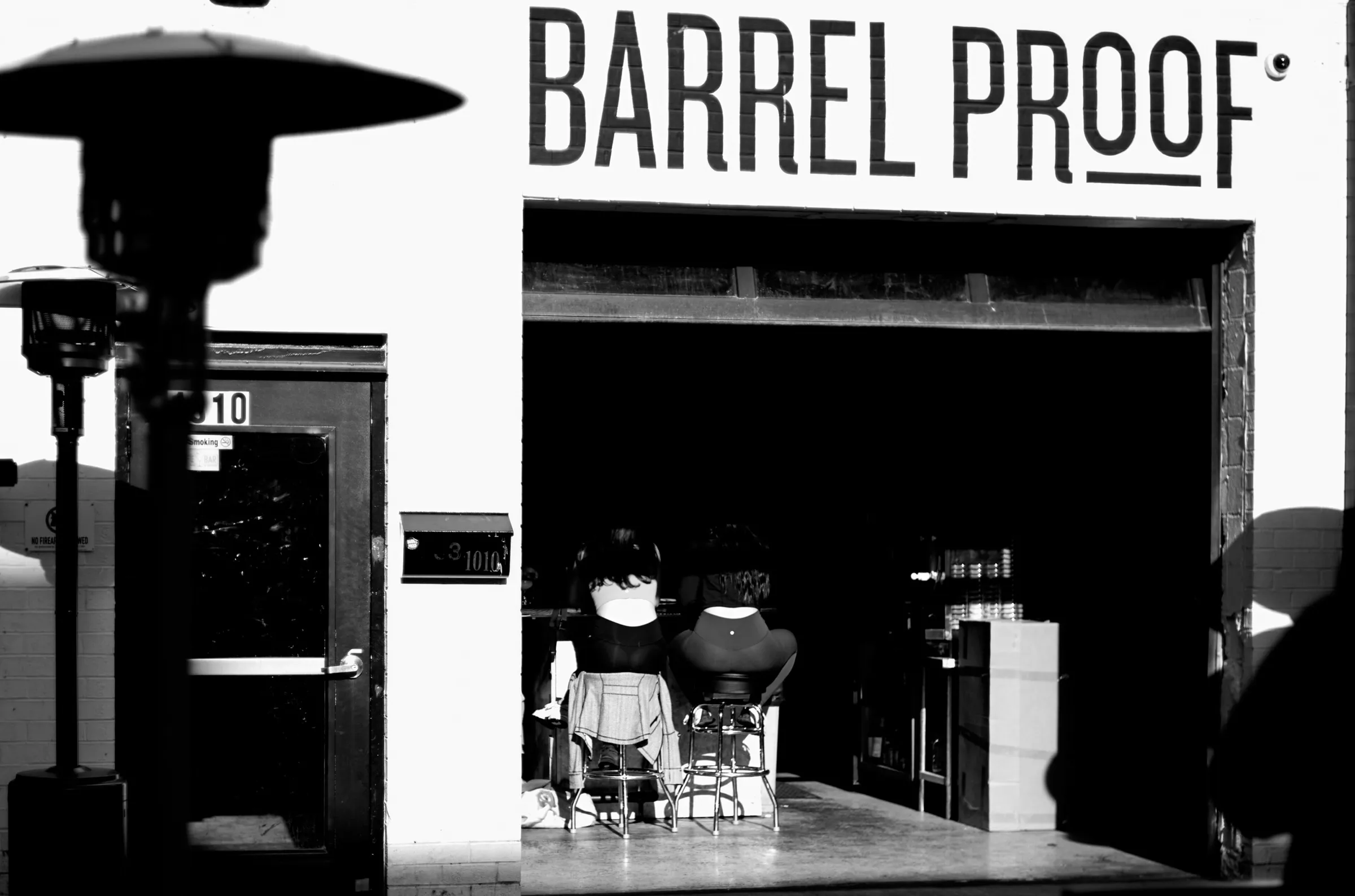 Barrel Proof bar exterior, two figures silhouetted in the open garage door