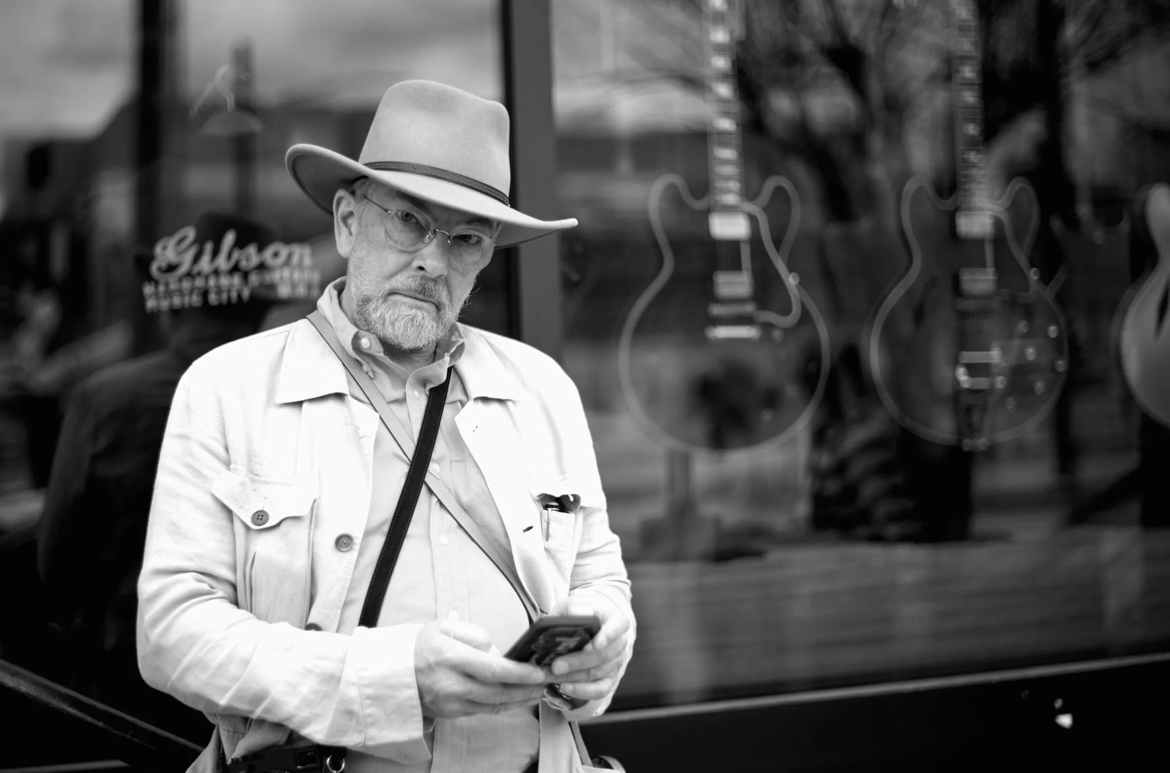 Thorsten Overgaard standing outside the Gibson store, checking his phone, guitar reflections in the window behind him