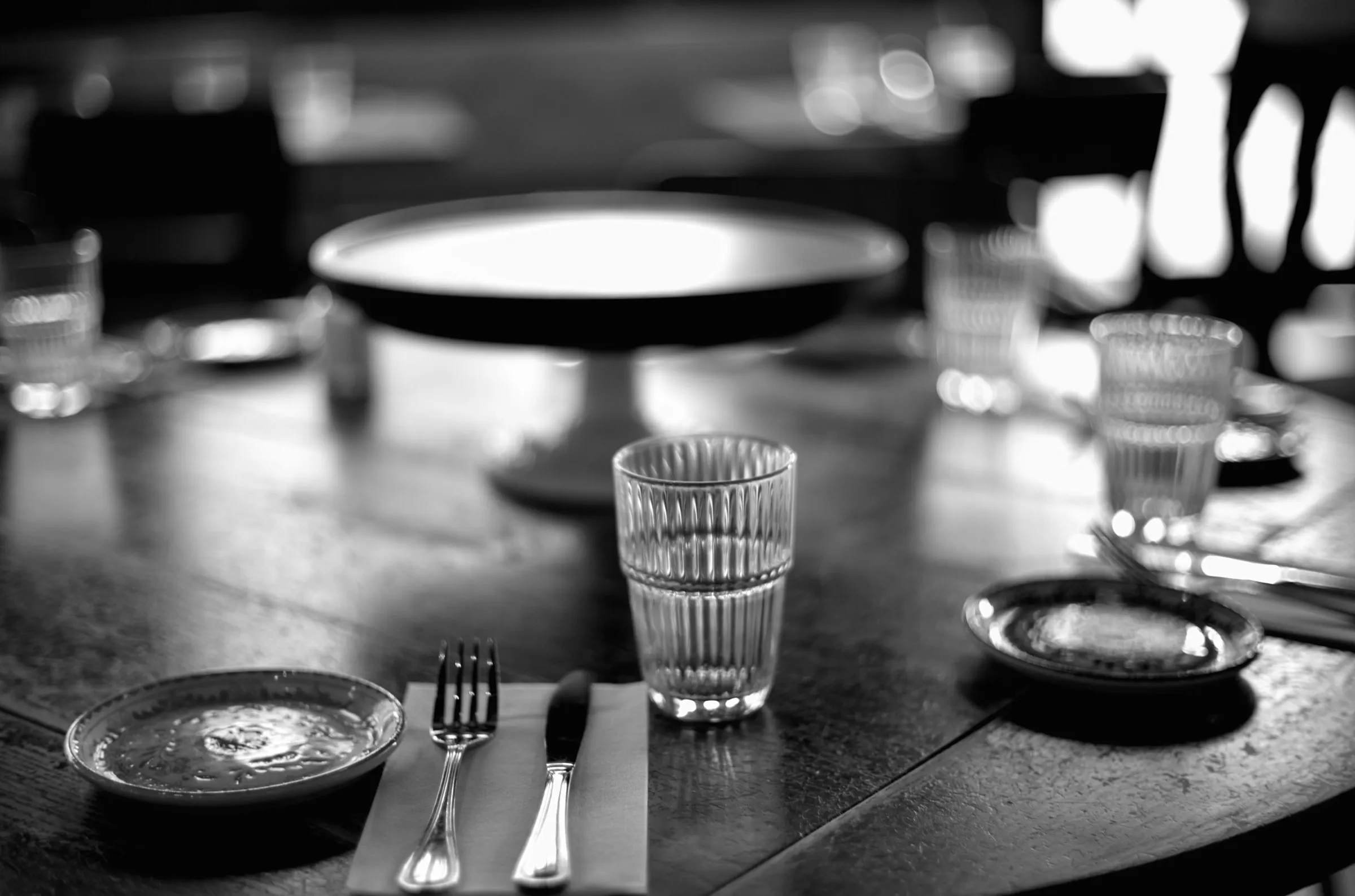 Set table at Superica restaurant, empty plates and glassware, soft window light
